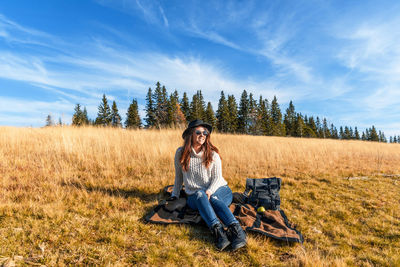 Woman sitting over picnic blanket on grass against sky