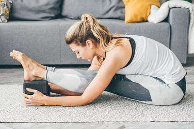 Side view of young woman exercising at home