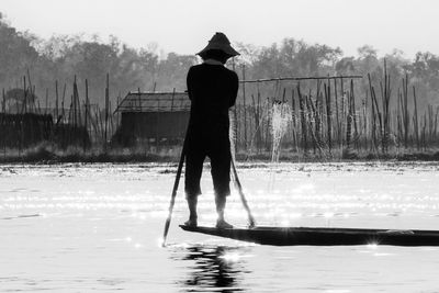 Rear view of man rowing boat in lake