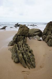 Rock on beach against sky