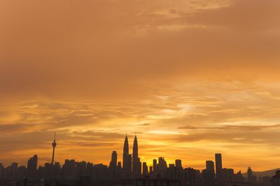 Silhouette of cityscape against orange sky during sunset