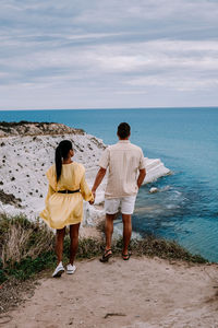 Rear view of couple on beach against sky