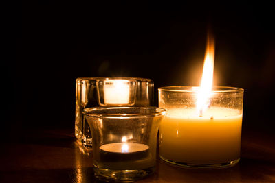 Close-up of tea light candle on table in dark room