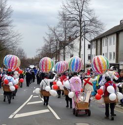 People at multi colored umbrellas in city against sky