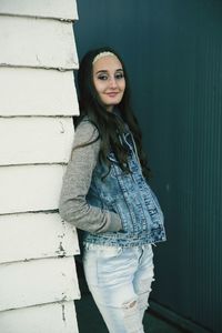 Portrait of young woman standing against wall