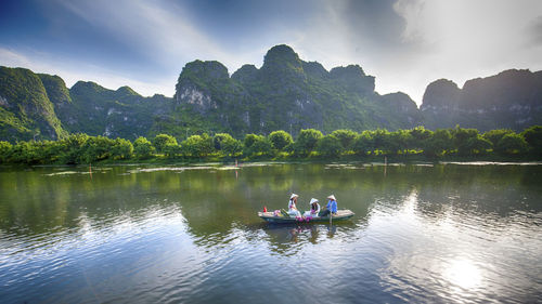 People on boat in lake against mountains