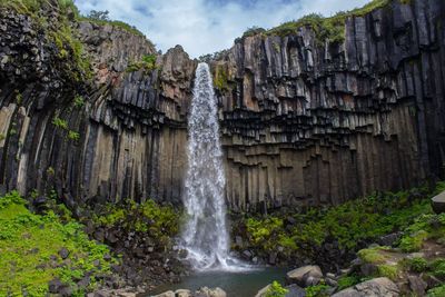 Scenic view of waterfall against sky