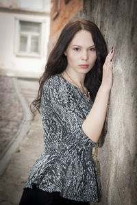 Portrait of beautiful young woman against wall