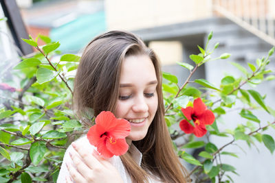 Portrait of beautiful woman holding red flowering plant