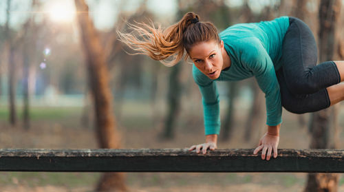 Portrait of woman exercising on bench in forest