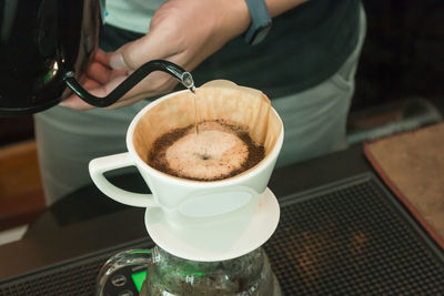 Close-up of hand holding coffee cup on table