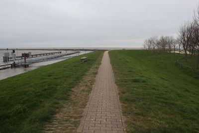 Footpath amidst field against sky