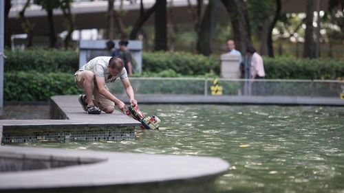 Man putting toy boat on swimming pool