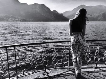 Rear view of woman standing by railing against sea