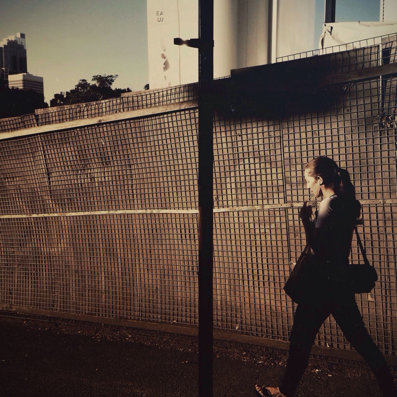 lifestyles, leisure activity, building exterior, built structure, architecture, shadow, silhouette, full length, standing, men, wall - building feature, walking, focus on shadow, side view, person, sunlight, fence, city