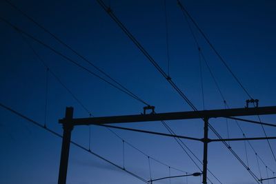 Low angle view of electricity pylon against blue sky