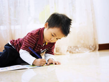 Boy coloring on book at home