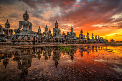 Statue of ancient buddha statues against sky during sunset