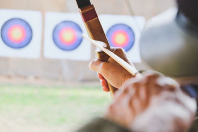 Cropped hands of woman with bow and arrow aiming at target