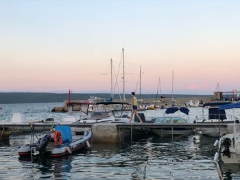 Sailboats moored in sea against sky during sunset