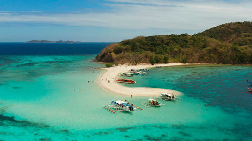 Tropical beach on island ditaytayan. tropical island with white sand bar, palm trees and green hills