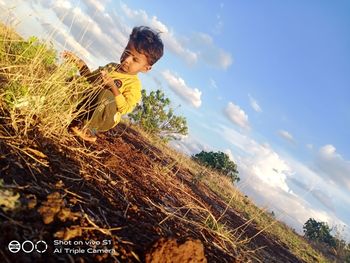 Rear view of boy with arms raised against sky