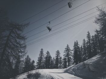 Low angle view of ski lift against sky during winter