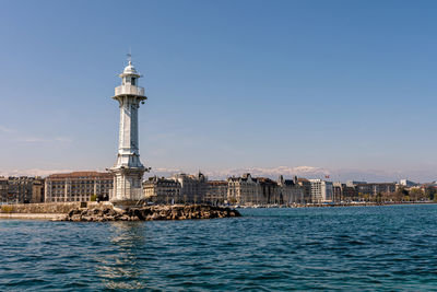 View of buildings by sea against blue sky