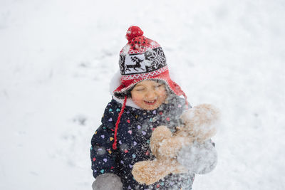 Cute little girl having fun playing outdoor during snowfall. 