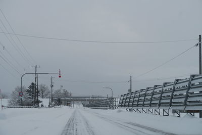 Snow covered railroad tracks against sky during winter