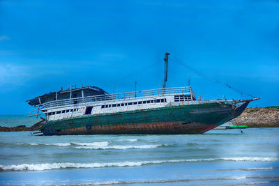 Sailboat on beach against blue sky