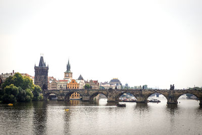 Arch bridge over river against sky in city