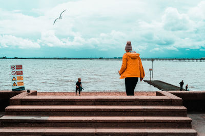 Rear view of women looking at sea against sky