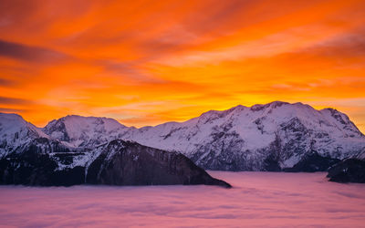 Scenic view of snowcapped mountains against orange sky