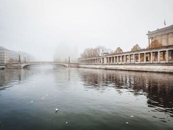 Bridge over river in foggy weather against sky