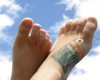 Close-up of hand holding hands against sky