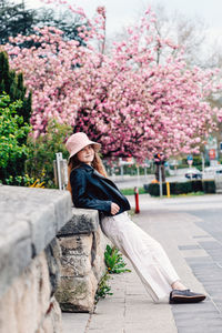 Rear view of girl sitting on retaining wall