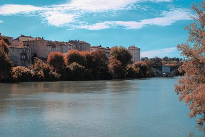 Scenic view of lake by buildings against sky during autumn