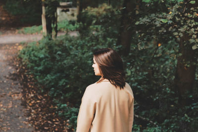 Rear view of woman standing against trees