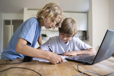 Boy assisting brother doing homework at home