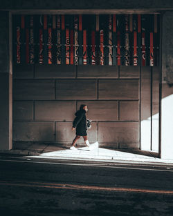 Full length of woman walking on street against building