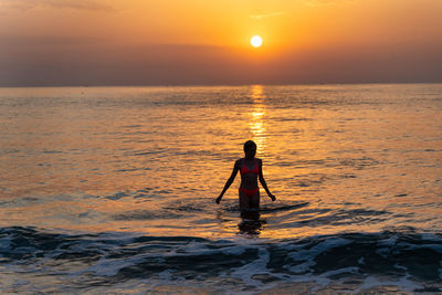 Silhouette person standing on beach during sunset