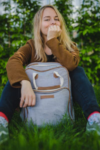 Portrait of young woman with blond hair sitting against plants