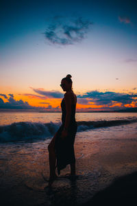 Silhouette man standing on beach against sky during sunset