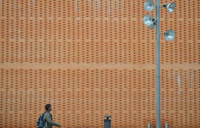 Man walking towards megaphones by brown wall