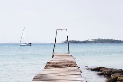 Sailboat on pier by sea against clear sky