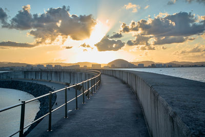 Bridge over sea against sky during sunset