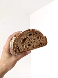 Cropped hand of person holding bread against white background