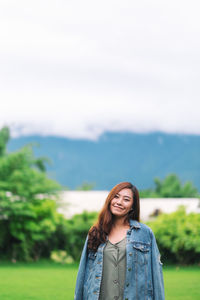 Portrait of smiling young woman standing against sky