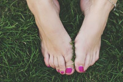 Low section of woman standing on grassy field